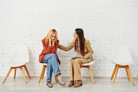 Dos mujeres elegantes que participan en una conversación profunda mientras están sentadas en sillas.