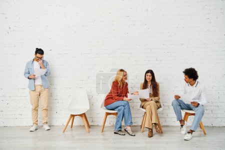 Foto de Un grupo de personas atractivas sentadas en sillas frente a una pared blanca. - Imagen libre de derechos