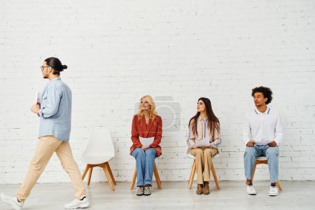 Group of people sitting in a row in front of a white wall.