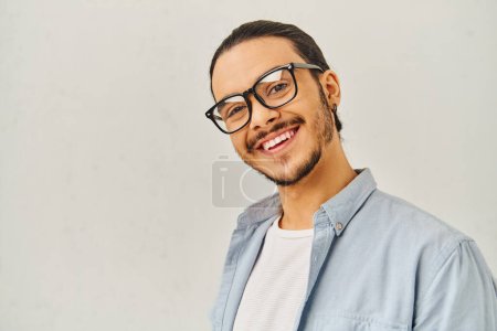 Photo for A man with glasses smiling brightly in a blue shirt. - Royalty Free Image