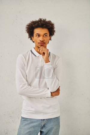 Young man in white polo shirt and jeans posing confidently.