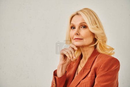 Photo for An older woman strikes a pensive pose, resting her hand on her chin. - Royalty Free Image