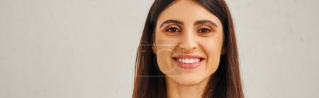 Photo for A woman smiling in front of a plain white backdrop. - Royalty Free Image