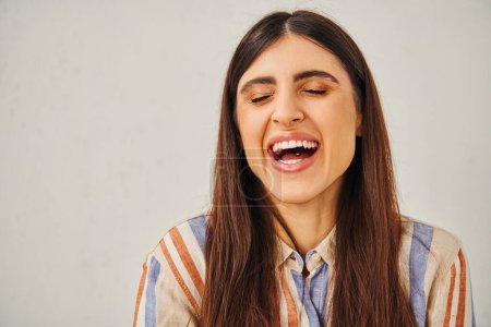 Una joven con la boca abierta, riendo alegremente.