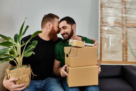 Schwules verliebtes Paar sitzt auf Couch, umgeben von Schachteln, hält Schachteln und Pflanzen, zieht gemeinsam in ein neues Zuhause.