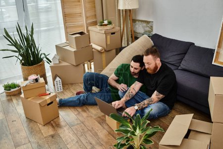 Zwei verliebte Männer machen eine Pause auf einem Sofa in einem neuen Zuhause voller Umzugskartons.