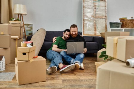 Photo for A man and a woman sit on the floor surrounded by boxes, focused on a laptop screen together. - Royalty Free Image
