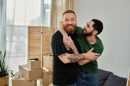 Two men, a gay couple, embrace lovingly in a living room filled with moving boxes. They are starting a new life together.