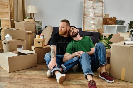 Ein liebevolles schwules Paar macht inmitten von Umzugskartons eine Pause und sitzt in einer gemütlichen Umarmung auf dem Holzboden ihres neuen Hauses.