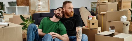 Couple of men nestled atop couch amidst new home move-in bustle.