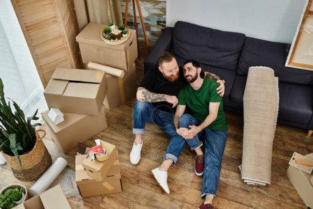 Ein schwules Paar sitzt auf einem Holzboden und betrachtet sein neues Leben zusammen, während sie in ihr neues Zuhause einziehen..