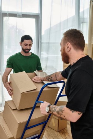 Foto de Busy day as a gay couple in love pack boxes in their new living room for a relocation and fresh start. - Imagen libre de derechos