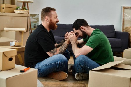 Zwei Männer, ein liebevolles schwules Paar, sitzen inmitten von Kisten in ihrem neuen Zuhause und beginnen gemeinsam ein neues Kapitel.