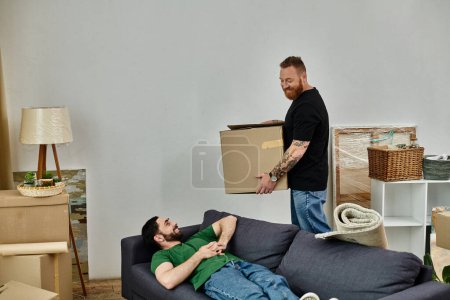 Un homme se trouve confortablement sur un canapé dans un salon encombré de boîtes mobiles, au milieu de l'excitation de commencer un nouveau chapitre de la vie.