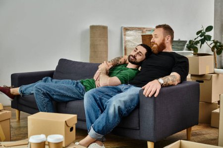 Schwules verliebtes Paar sitzt auf Couch, umgeben von gepackten Kisten, und beginnt ein neues Kapitel in ihrer Lebensreise.