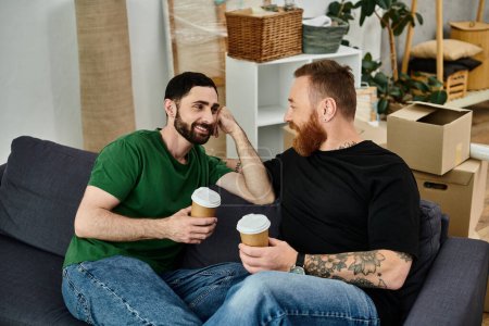Zwei Männer sitzen auf einer Couch und unterhalten sich lebhaft bei einer Tasse Kaffee.