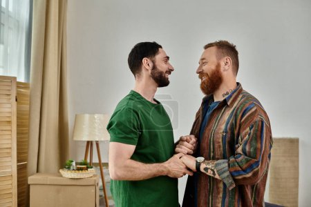 A gay couple stands amidst moving boxes, beginning their new life together in a new home.