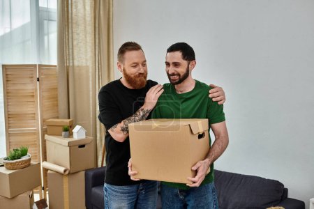 Foto de Pareja gay de pie juntos en sala de estar rodeado por mover cajas, comenzando fresco en nuevo hogar. - Imagen libre de derechos