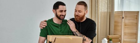Foto de Dos hombres, parte de una pareja gay amorosa, se paran uno al lado del otro sosteniendo una caja en su nuevo hogar - Imagen libre de derechos