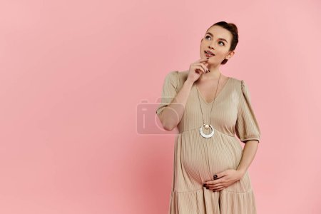 Pregnant woman in a dress striking a pose on a pink background.