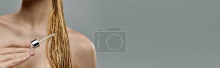 Téléchargez les photos : Femme séduisante tenant un sérum capillaire, affichant sa routine de soins capillaires avec des cheveux mouillés. - en image libre de droit