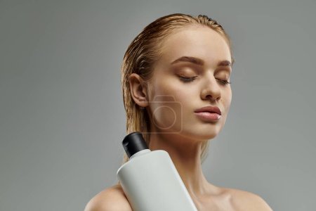 Alluring woman sensually holds a bottle of hair treatment.