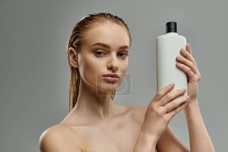 A woman gracefully holds a bottle of shampoo.