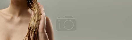 Téléchargez les photos : Une jeune belle femme présentant ses longs cheveux mouillés sur fond gris. - en image libre de droit