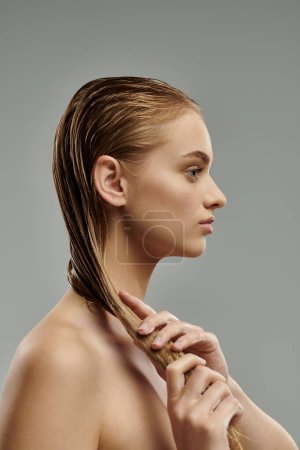 Photo for Young woman with long hair tenderly applying hair care products. - Royalty Free Image
