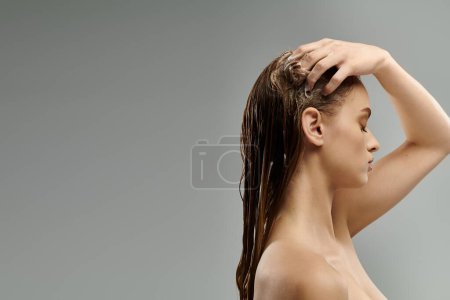 Belleza de pelo largo revela su rutina de cuidado del cabello contra un telón de fondo gris.