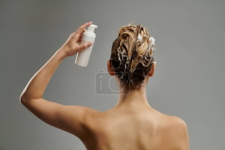 Anspruchsvolle Frau, die Haarpflegemittel anwendet und Haare wäscht.