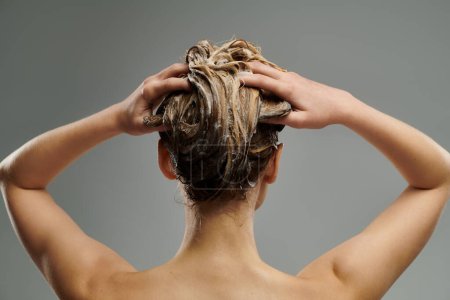 Una joven mujer demuestra su rutina de cuidado del cabello con el pelo mojado.