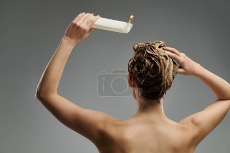 Schöne Frau hält eine Tube Shampoo.