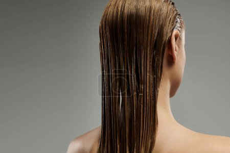 A young woman showcases her hair care routine with wet, flowing locks.
