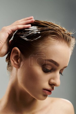 A young woman delicately holds her wet hair in her hand, showcasing her hair care routine.