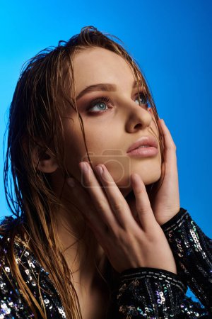 A young beautiful woman with her hand on her face, showcasing her wet hair.