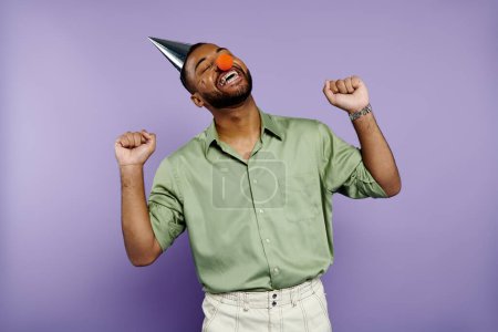 A jubilant young African American man wearing braces and party hat against a vibrant purple backdrop.