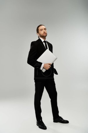 A bearded businessman in a sharp suit holds a crucial document, exuding confidence and professionalism against a grey backdrop.