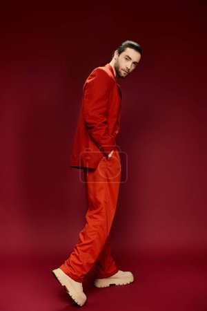 Photo for A stylish man with a red suit and no shirt striking a pose in a studio setting. - Royalty Free Image