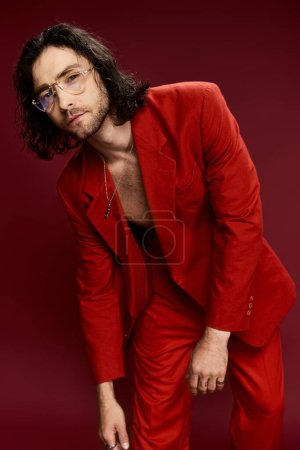 Foto de Un hombre guapo con un llamativo traje rojo y gafas posa con confianza, exudando estilo y sofisticación. - Imagen libre de derechos