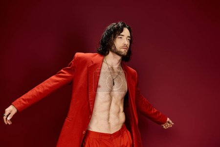 Téléchargez les photos : Un homme fringant dans un costume rouge se tient avec confiance avec sa chemise ouverte dans une pose frappante. - en image libre de droit