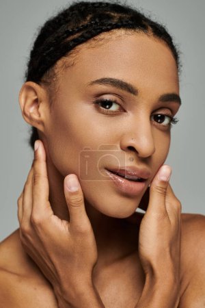Beautiful African American woman delicately touching her face with care, exuding grace and poise.