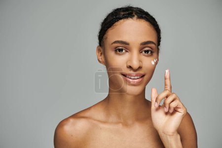 Photo for A beautiful young African American woman, topless, holds up a peace sign against a grey background. - Royalty Free Image
