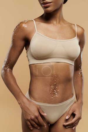 Foto de Una cautivadora mujer afroamericana en lencería irradia confianza y belleza sobre un suave fondo beige. - Imagen libre de derechos