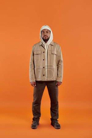 Photo for Stylish African American man posing on vibrant orange backdrop. - Royalty Free Image