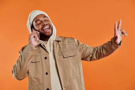 Homme afro-américain élégant en veste bronzée parlant sur un téléphone portable.