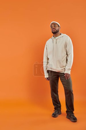 Foto de Hombre afroamericano posando sobre un fondo naranja brillante. - Imagen libre de derechos