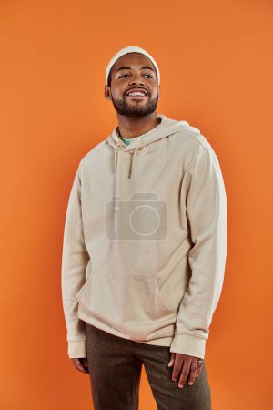 Confident African American man striking a pose against a vibrant orange background.
