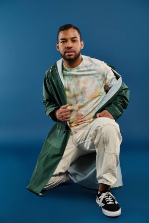 A stylish African American man sitting boldly in a vibrant green coat.