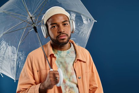 Stylish man with headphones holding an umbrella.